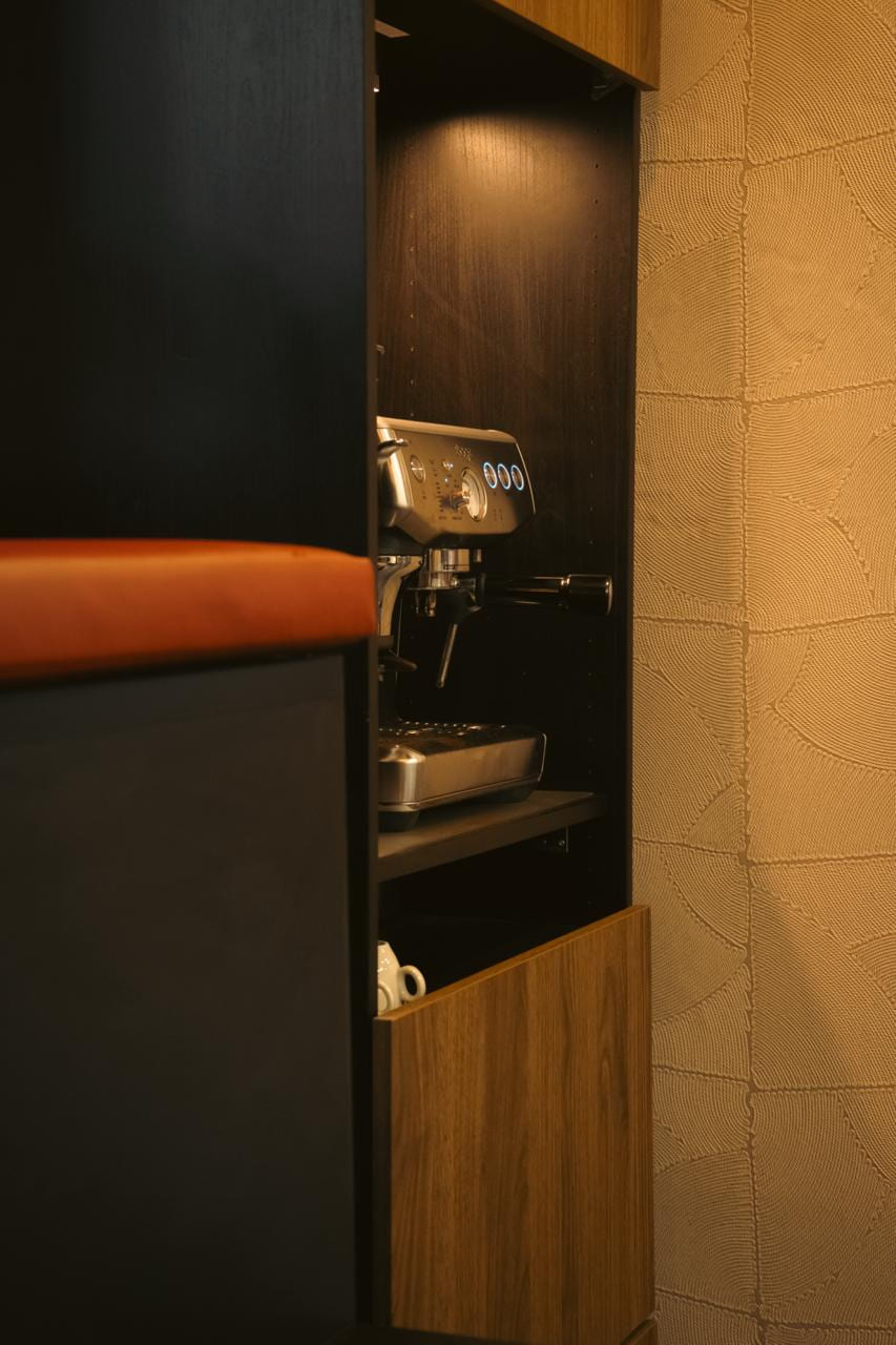 Espressomachine in een verlichte nis van de kast, kopjes eronder.