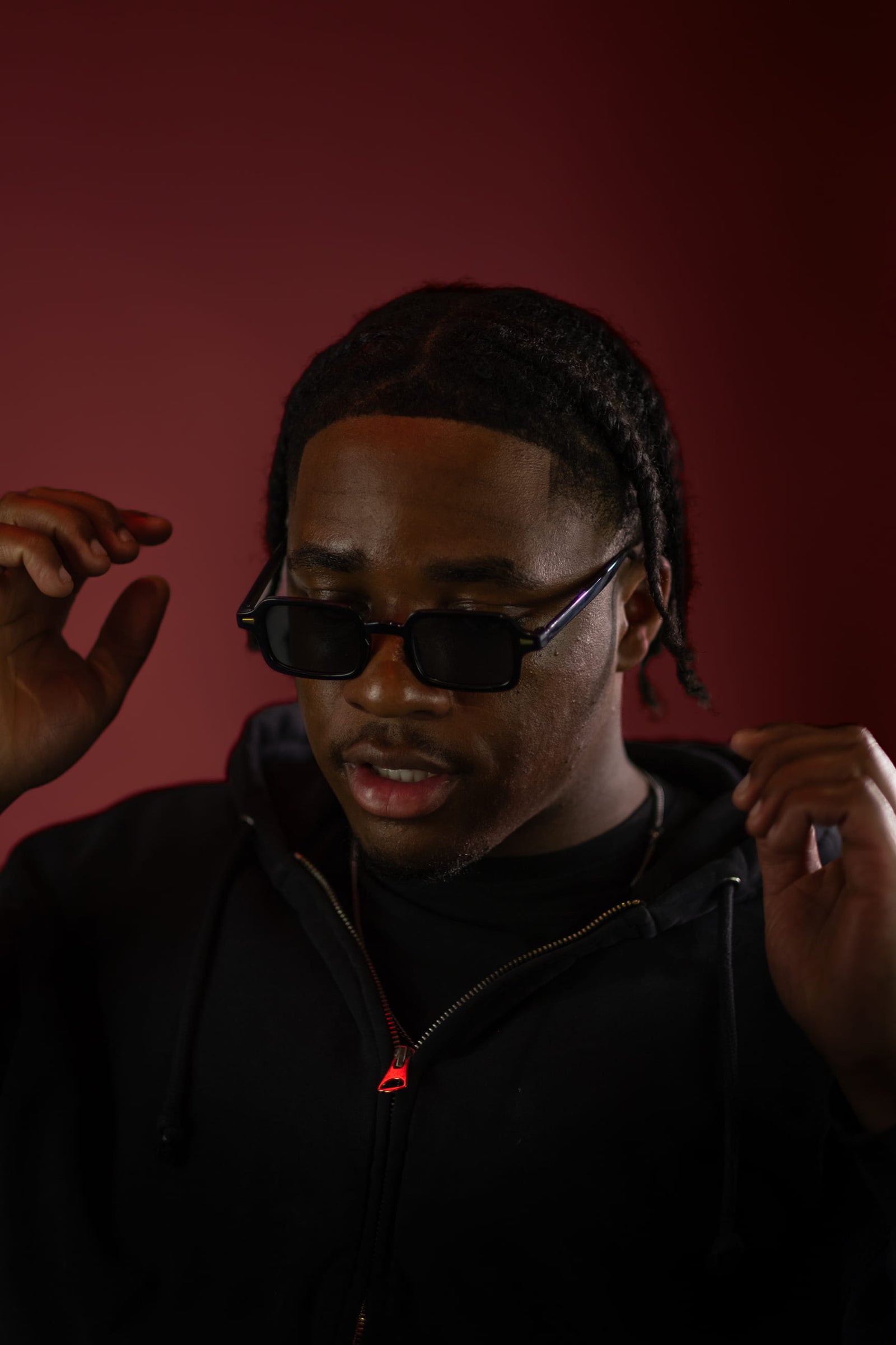Cornrows, handen bij het gezicht; diep karmijnrood doek.