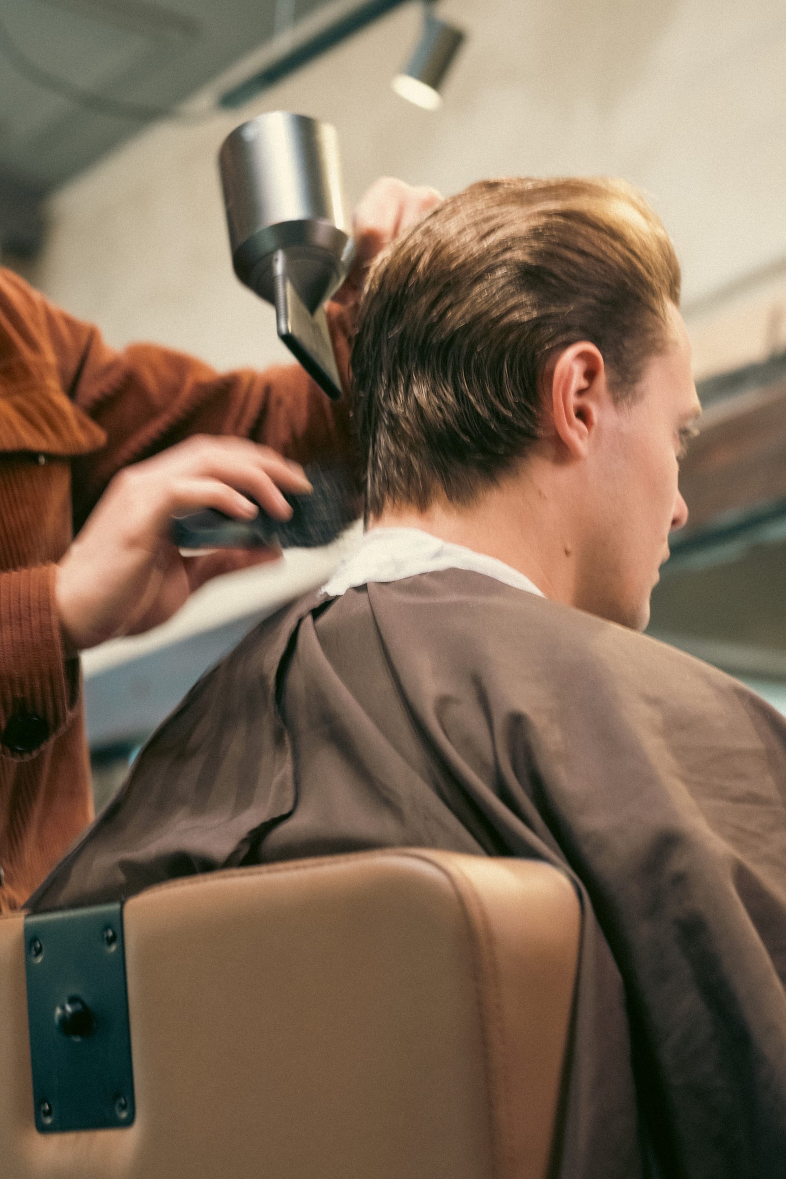 Barber föhnt en borstelt het achterhoofd na de knipbeurt.