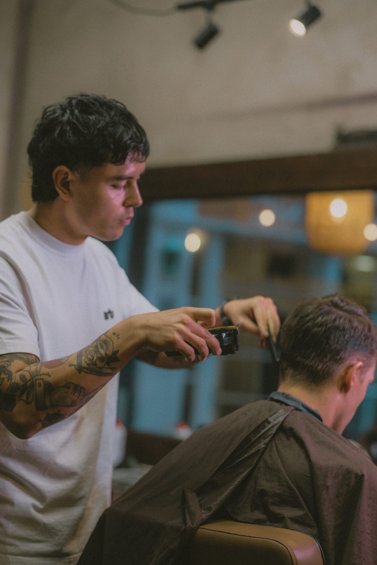 Barber zet tondeuse en kam in de nek; het interieur onscherp erachter.